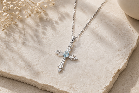 Faith Cross Necklace in sterling silver with blue topaz gemstone on neutral background