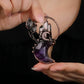 Hand holding natural amethyst crescent moon celestial pendant