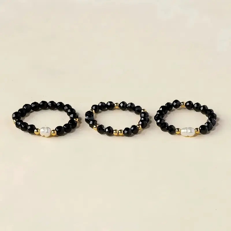 Black spinel and freshwater pearl rings shown in three coordinating designs