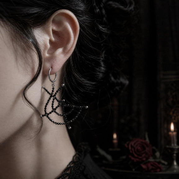 Black spinel spiderweb earrings worn with gothic styling