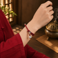 Persimmon Wish red cord bracelet worn on wrist with silver-plated copper charm