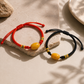 Red and black adjustable cord AI companion bracelets with yellow core bead