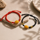 Red and black adjustable cord AI companion bracelets with yellow core bead