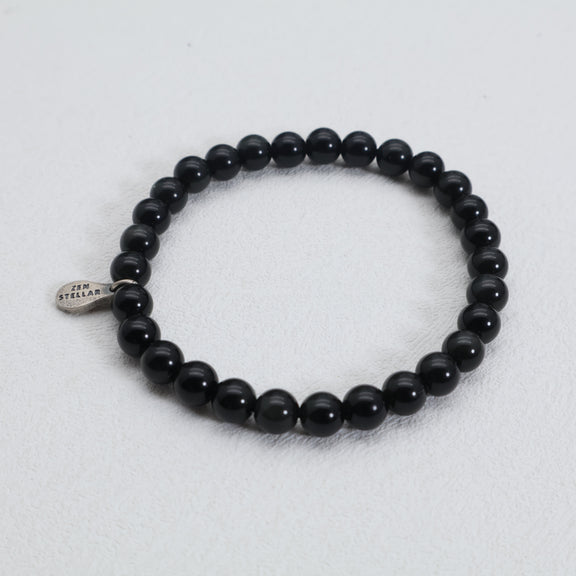Detail of the 925 sterling silver charm on a black obsidian bead bracelet