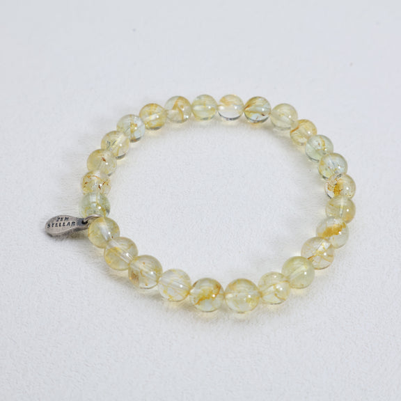 Full view of the Golden Radiance topaz bracelet showing round golden beads, natural inclusions, and a silver charm