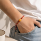 Red adjustable cord AI companion bracelet worn on wrist